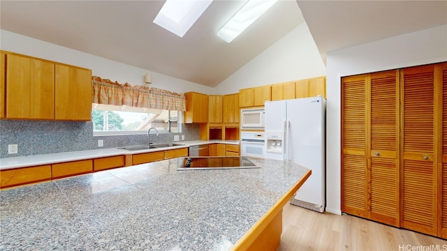 kitchen with decorative backsplash, a skylight, white appliances, sink, and light hardwood / wood-style floors