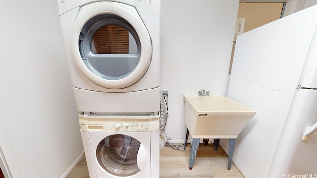 laundry area with stacked washing maching and dryer and light wood-type flooring