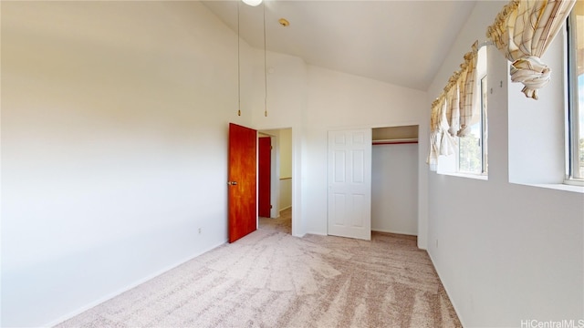 unfurnished bedroom featuring light carpet, high vaulted ceiling, and a closet