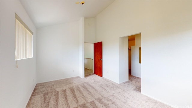 spare room featuring light carpet and a towering ceiling