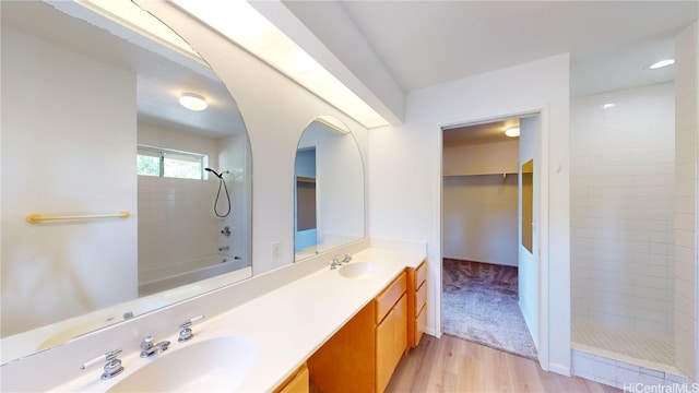 bathroom featuring wood-type flooring, vanity, and tiled shower / bath