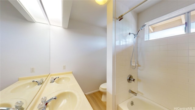 full bathroom featuring hardwood / wood-style floors, vanity, toilet, and tiled shower / bath