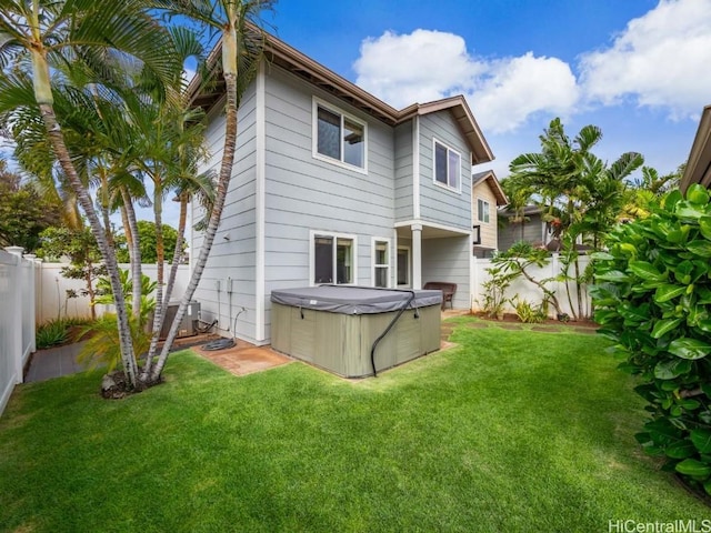 rear view of property featuring central air condition unit, a hot tub, and a lawn