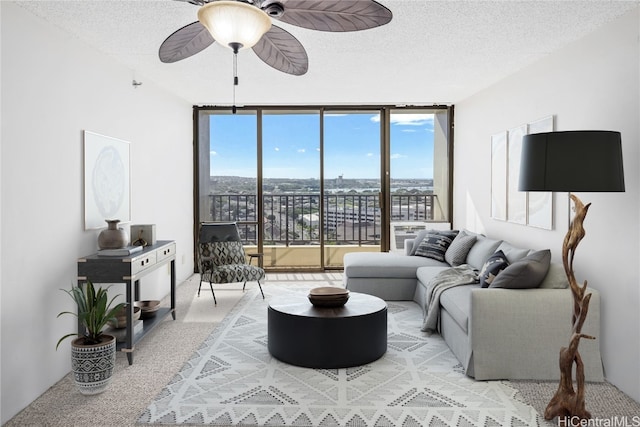 carpeted living room featuring ceiling fan, expansive windows, and a textured ceiling