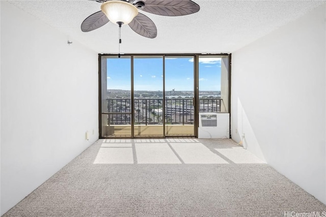 empty room featuring ceiling fan, floor to ceiling windows, light colored carpet, and a textured ceiling