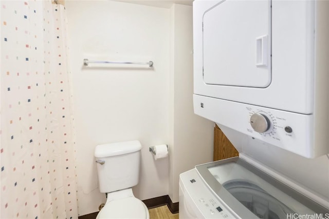 bathroom with a shower with shower curtain, toilet, and stacked washer / dryer