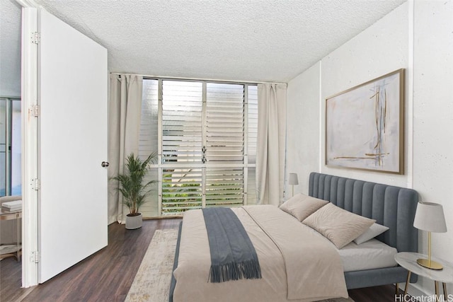 bedroom with expansive windows, a textured ceiling, and dark wood-type flooring