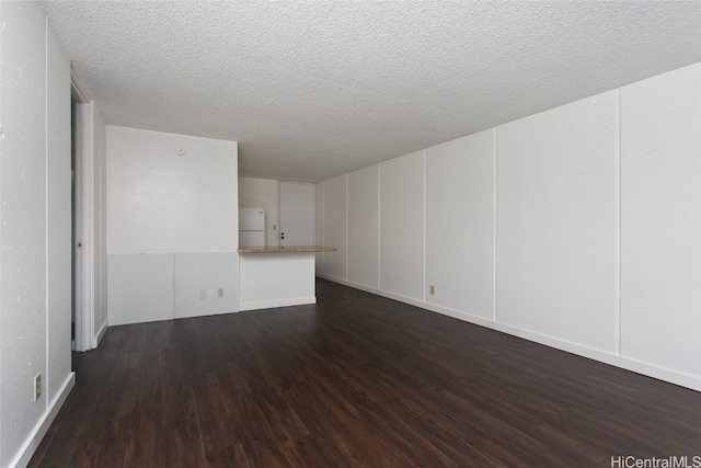 empty room with a textured ceiling and dark wood-type flooring