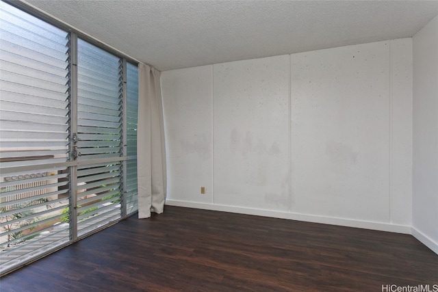 spare room featuring dark wood-type flooring and a textured ceiling