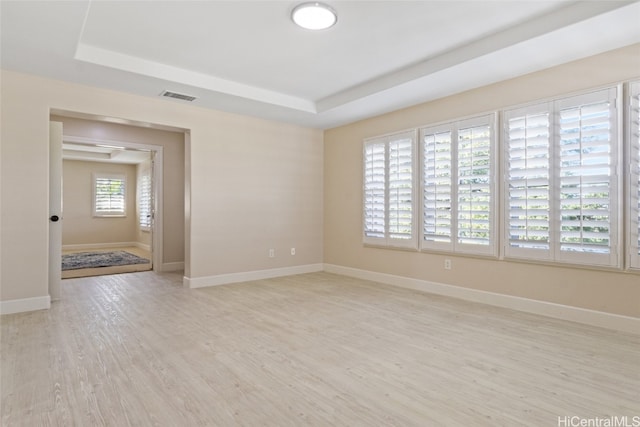 unfurnished room with a raised ceiling and light wood-type flooring