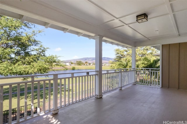 view of patio with a balcony and a water and mountain view