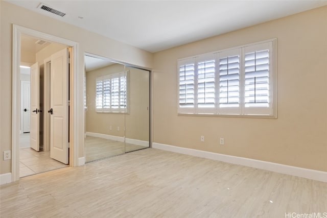 unfurnished bedroom with light hardwood / wood-style flooring and a closet