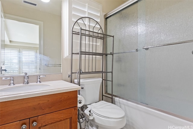 full bathroom featuring vanity, toilet, and bath / shower combo with glass door