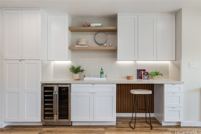 bar featuring white cabinets, light wood-type flooring, and beverage cooler