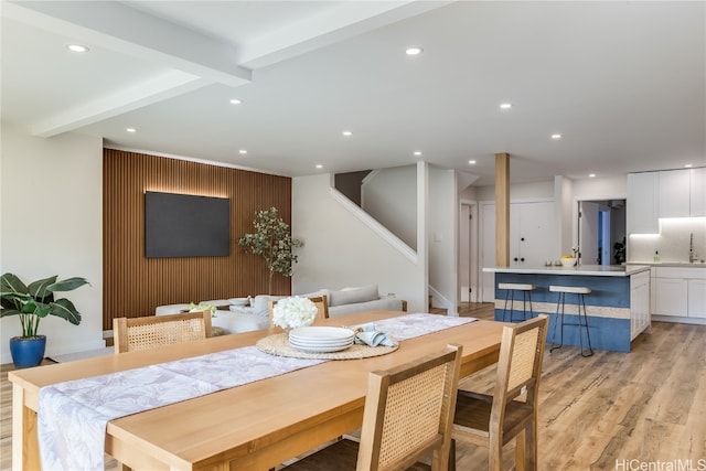 dining space with beam ceiling and light hardwood / wood-style flooring