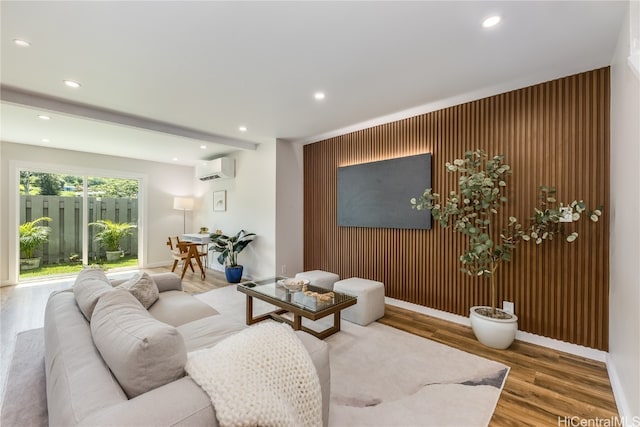 living room with a wall unit AC, wood walls, and hardwood / wood-style flooring