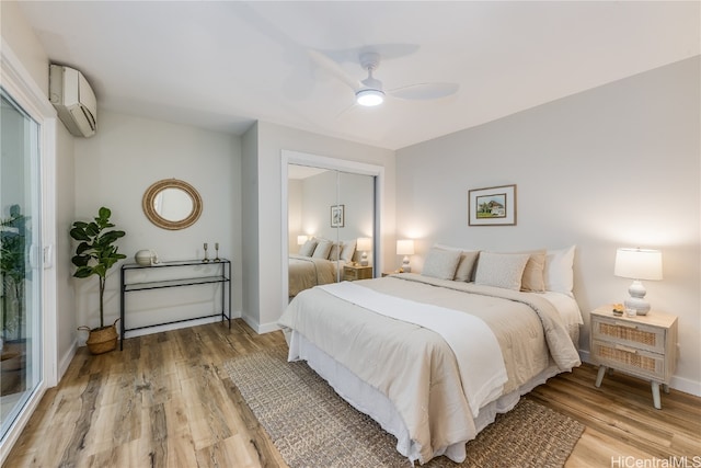 bedroom featuring a wall mounted AC, ceiling fan, a closet, and light hardwood / wood-style floors