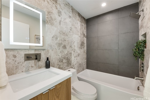 full bathroom with vanity, tiled shower / bath combo, tile walls, and toilet