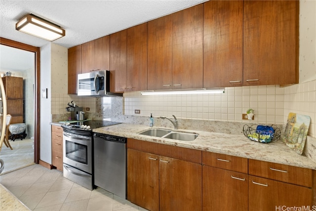 kitchen with sink, stainless steel appliances, backsplash, a textured ceiling, and light tile patterned flooring