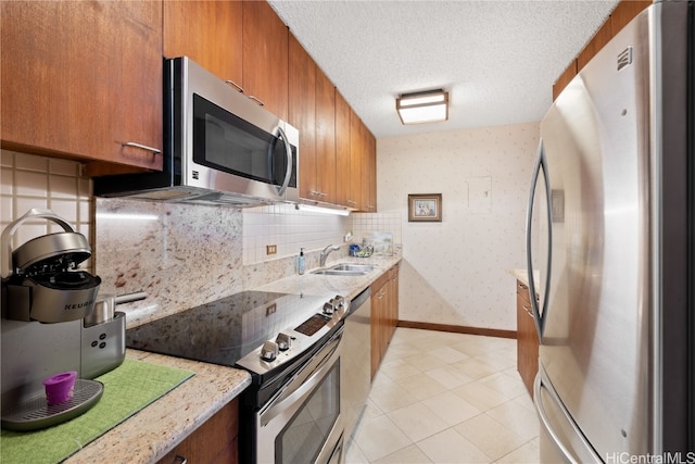 kitchen featuring light stone counters, sink, a textured ceiling, and appliances with stainless steel finishes