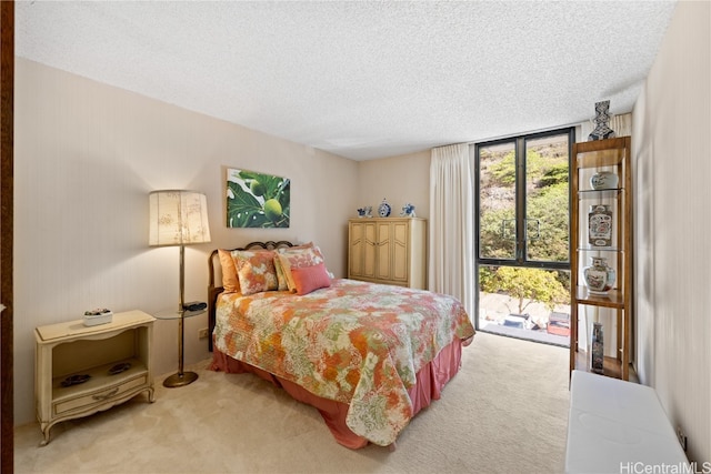 carpeted bedroom with a textured ceiling, access to outside, and expansive windows