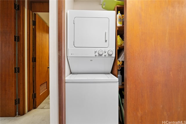 laundry room with stacked washer / dryer and light carpet