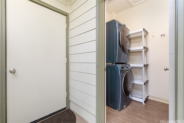 washroom with hardwood / wood-style floors and stacked washer and clothes dryer