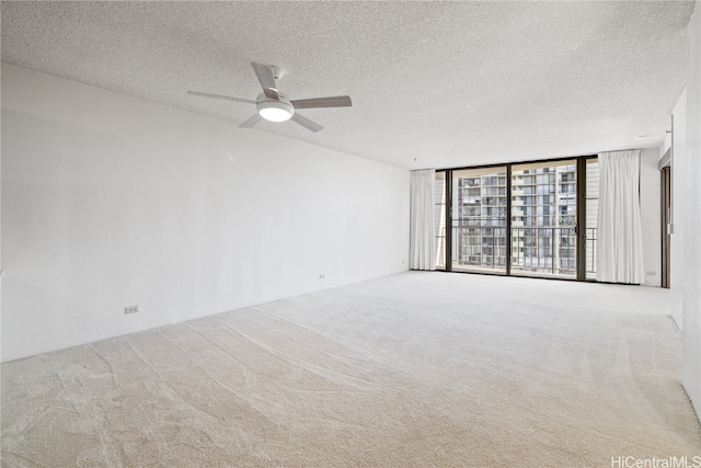 carpeted empty room with a textured ceiling, expansive windows, and ceiling fan