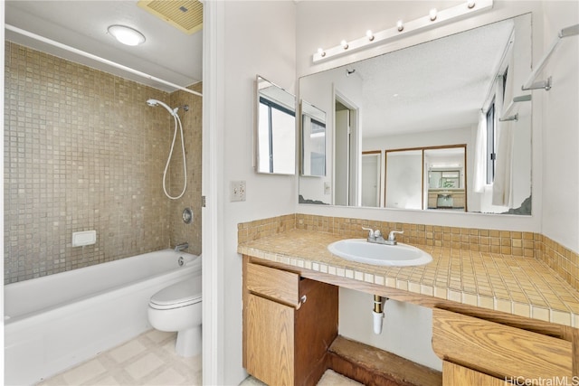 full bathroom featuring tiled shower / bath combo, toilet, and sink