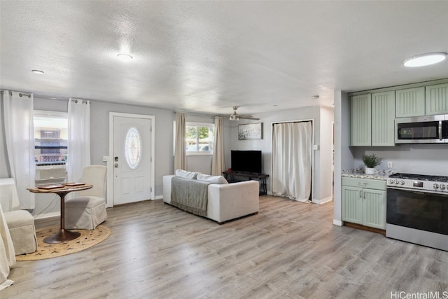 living room featuring ceiling fan, a textured ceiling, and light wood-type flooring