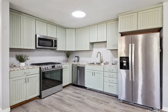 kitchen featuring light stone countertops, sink, stainless steel appliances, and light hardwood / wood-style floors