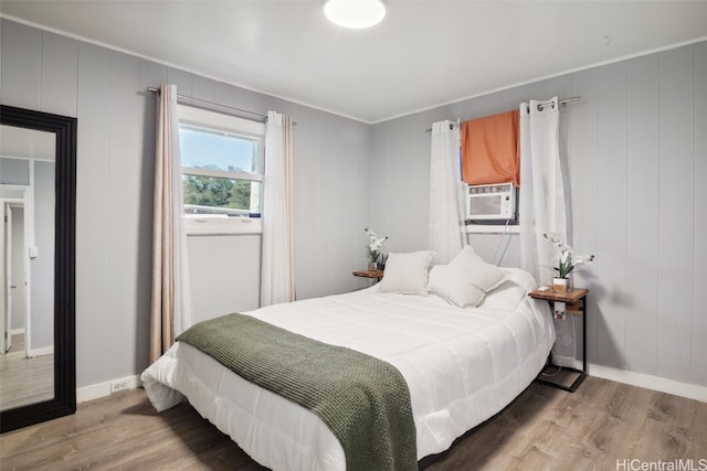 bedroom with crown molding, cooling unit, and hardwood / wood-style flooring