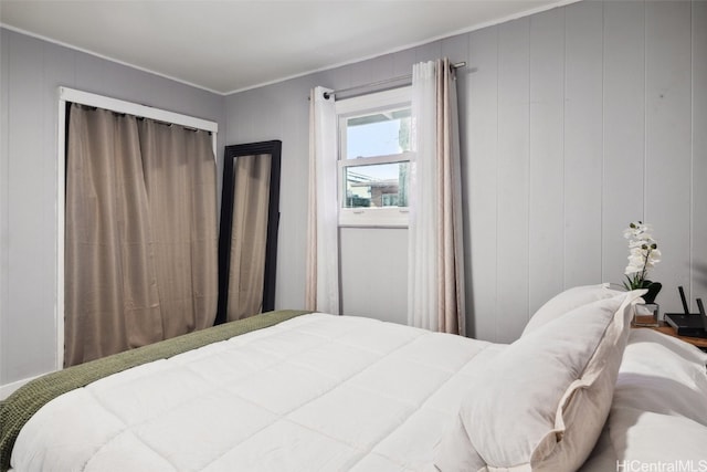 bedroom with ornamental molding and wooden walls