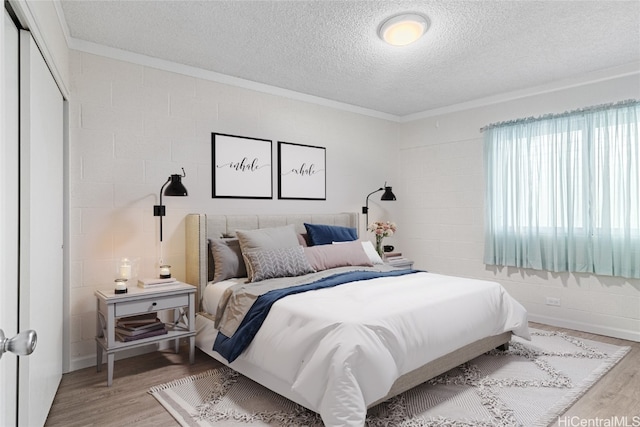 bedroom featuring hardwood / wood-style flooring, crown molding, a textured ceiling, and a closet