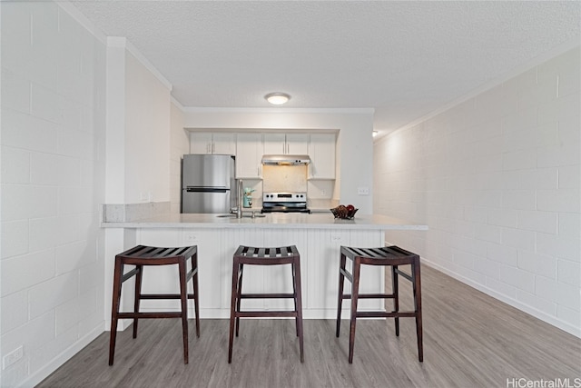 kitchen with kitchen peninsula, stainless steel fridge, stove, white cabinets, and light wood-type flooring