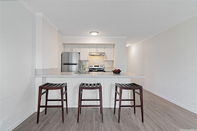1642 Kewalo St Unit 208, Honolulu, HI 96822 - kitchen with electric stove, freestanding refrigerator, under cabinet range hood, light wood-style flooring, and crown molding
