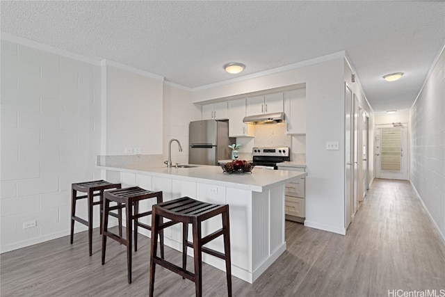 kitchen with sink, light hardwood / wood-style flooring, a kitchen bar, kitchen peninsula, and stainless steel appliances