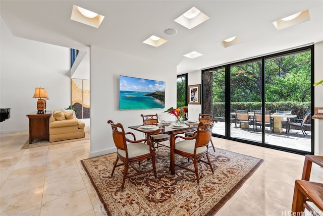 dining room featuring a skylight, light tile patterned flooring, and a wall of windows