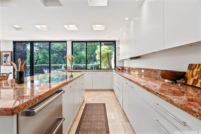 kitchen with light stone countertops, white cabinetry, and light tile patterned floors