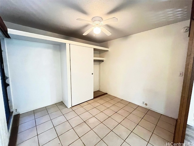 unfurnished bedroom featuring ceiling fan, light tile patterned floors, and a closet