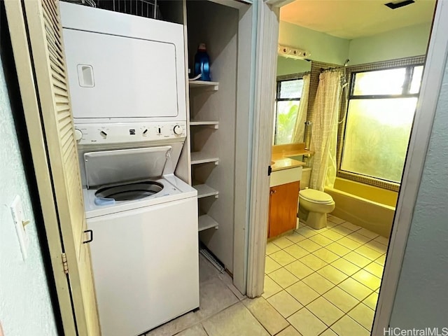 laundry area with stacked washer / dryer and light tile patterned flooring