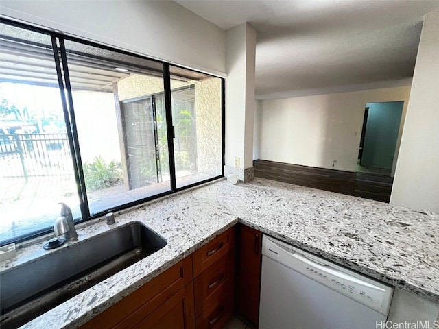 kitchen with hardwood / wood-style flooring, dishwasher, light stone counters, and sink