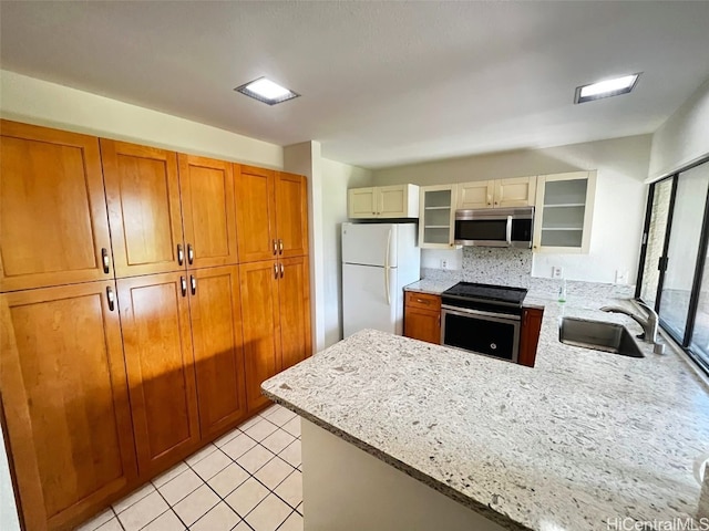 kitchen with light stone countertops, sink, kitchen peninsula, light tile patterned floors, and appliances with stainless steel finishes