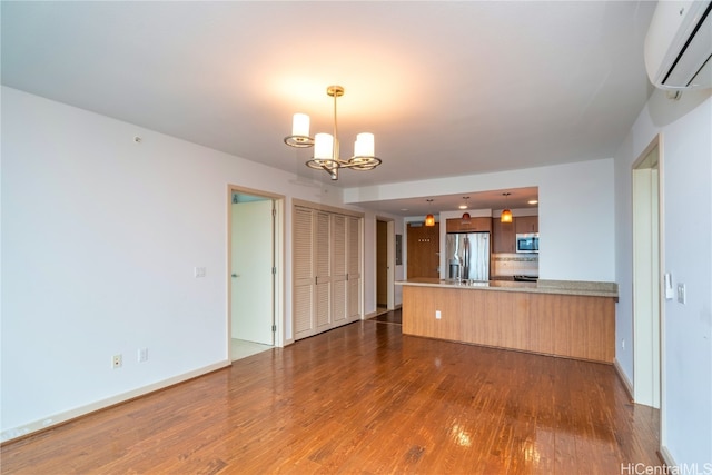 unfurnished living room with a notable chandelier, dark hardwood / wood-style floors, and an AC wall unit