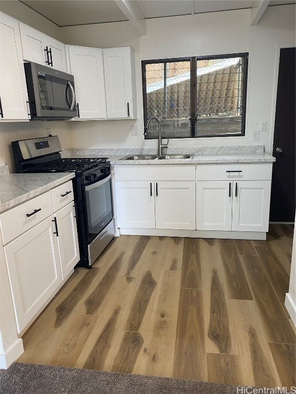 kitchen with hardwood / wood-style flooring, white cabinetry, sink, and appliances with stainless steel finishes