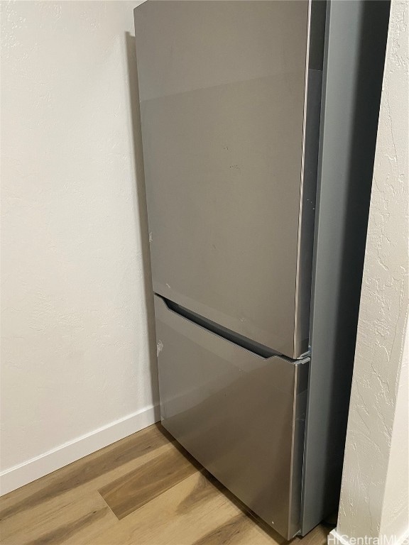 room details with stainless steel fridge and hardwood / wood-style flooring