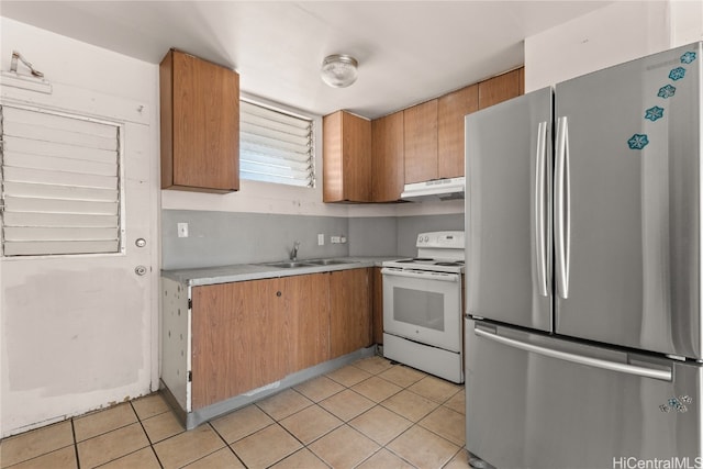 kitchen with white range with electric cooktop, light tile patterned floors, stainless steel refrigerator, and sink