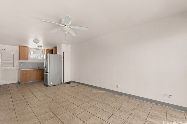 interior space with stainless steel fridge, light tile patterned floors, and ceiling fan