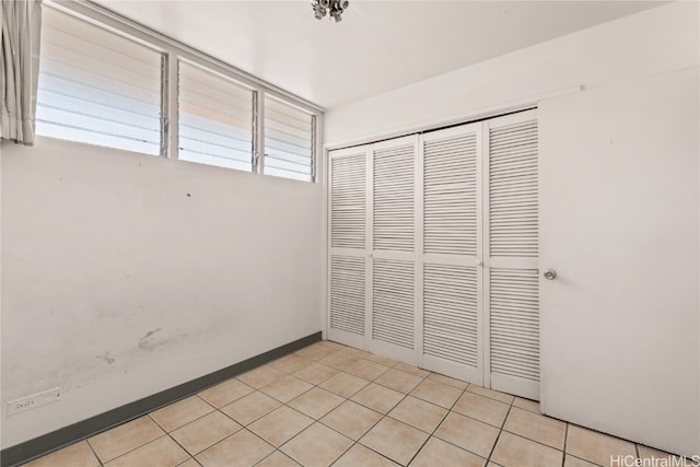 unfurnished bedroom with light tile patterned floors, a closet, and multiple windows