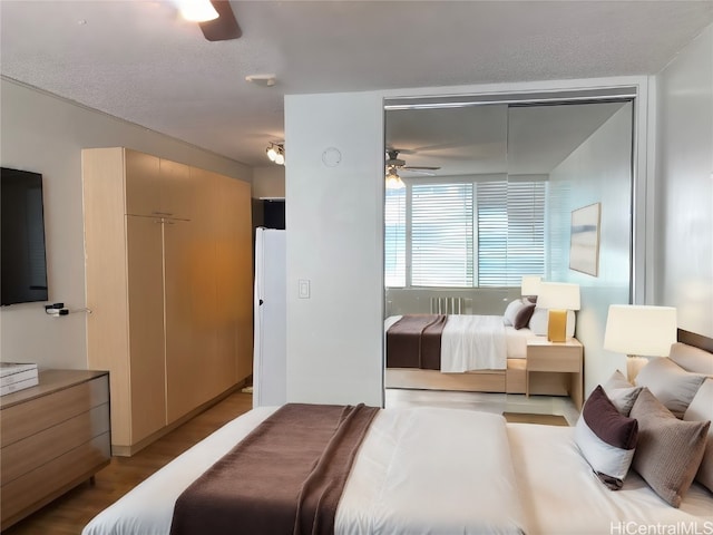 bedroom featuring ceiling fan, light hardwood / wood-style floors, a textured ceiling, and a closet